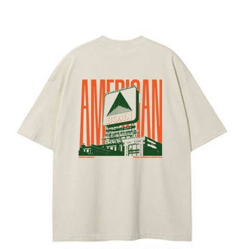 A beige oversized t-shirt featuring a graphic of a vintage sign with "AMERICAN BORN"