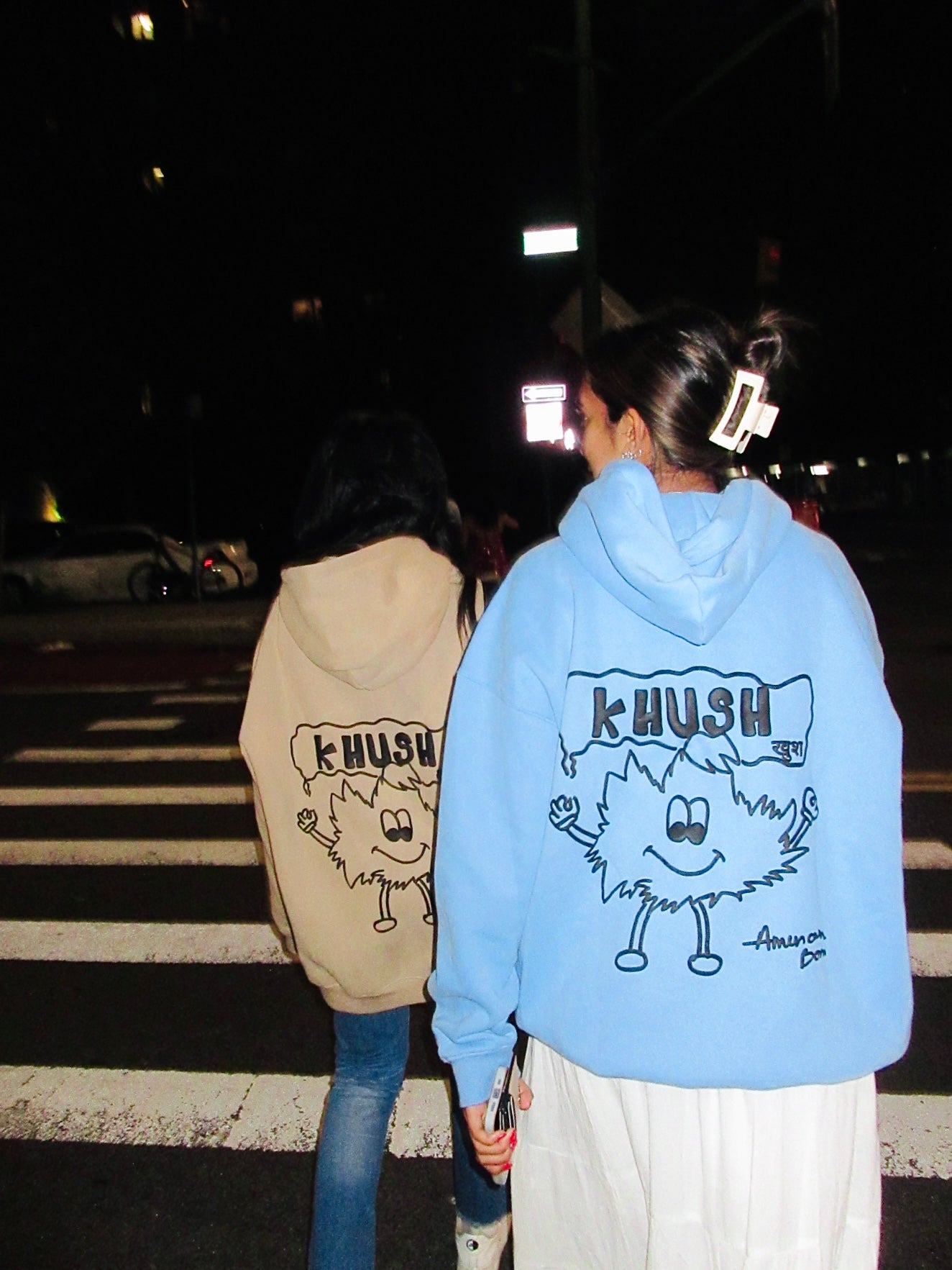 Two women wearing oversized hoodies: one beige and one light blue